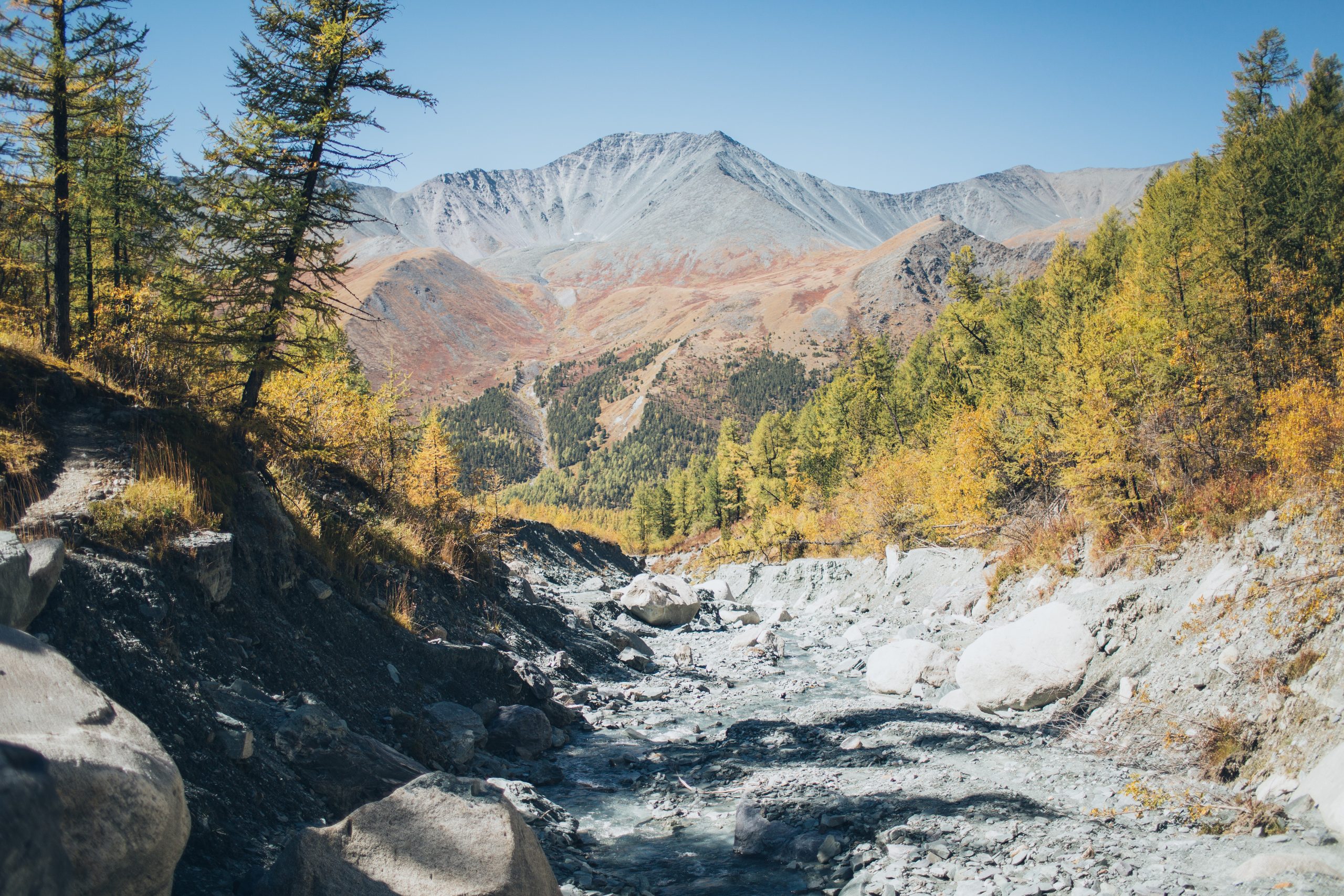 photo-of-rocky-river-near-green-trees-and-brown-mountains-4275975